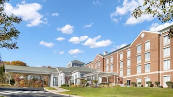A hotel with a brick facade, a covered entrance, and a well-maintained lawn.