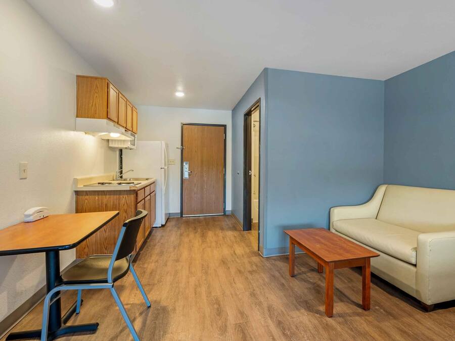 A compact living space with a kitchenette, a dining area with a table and chairs, and a sofa.