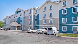A multi-story hotel with a central entrance, parking area, and several vehicles parked in front.