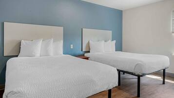 A hotel room with two beds, a wooden floor, and a blue wall.
