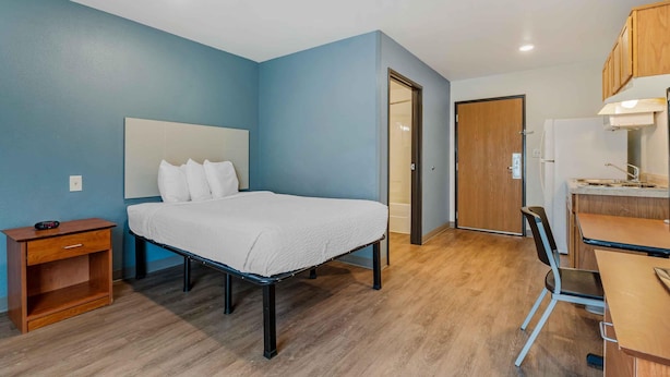 A bedroom with a bed, bedside table, and a desk with a chair.