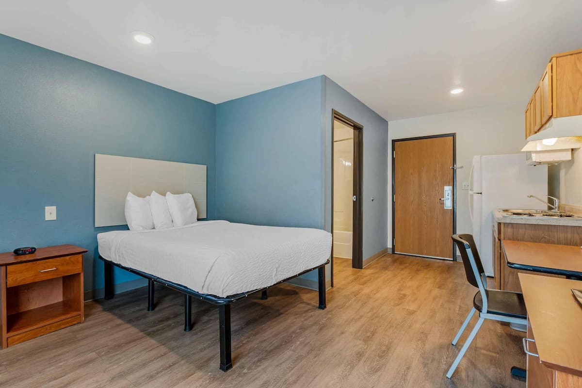 Un dormitorio con cama, mesita de noche y escritorio con silla.