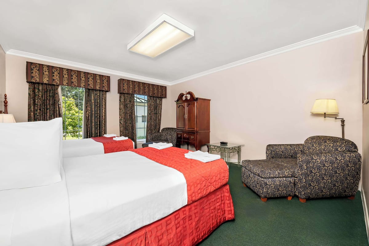 A hotel room with a large bed, two armchairs, a small table, and a cabinet.