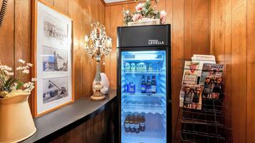 Un mini bar con un refrigerador, un florero y un mueble para revistas.