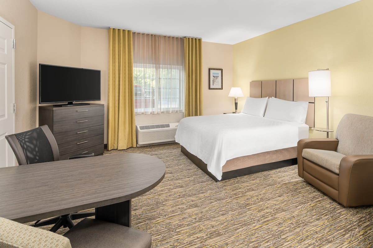 A hotel room with a bed, a TV, a desk, a chair, and a lamp.