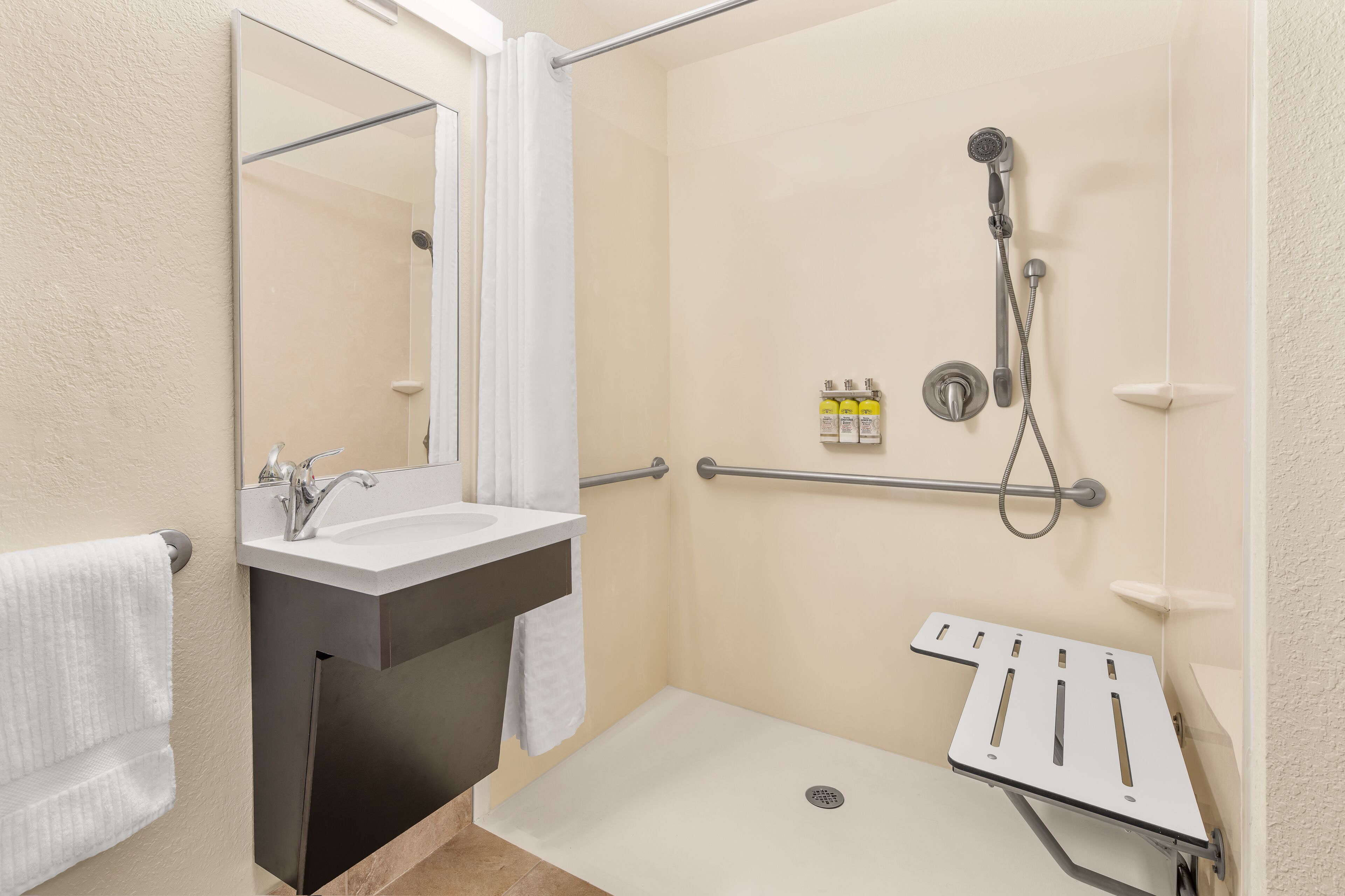 Un baño moderno con ducha, lavamanos, espejo y toallero.