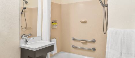 A modern bathroom with a bathtub, a shower, a sink, and a mirror.