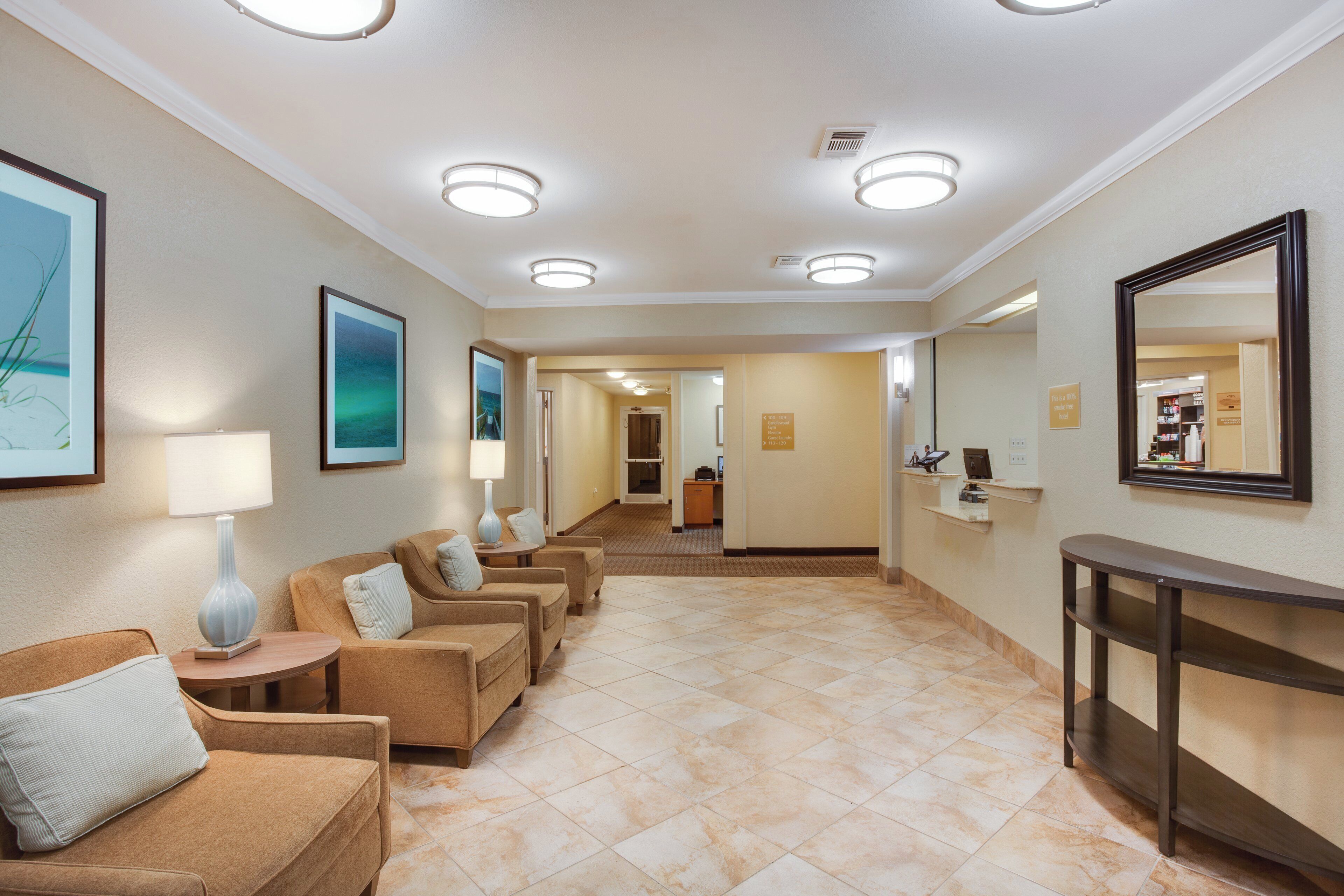 A hotel lobby with a reception desk, seating area with chairs, and a hallway leading to other rooms.