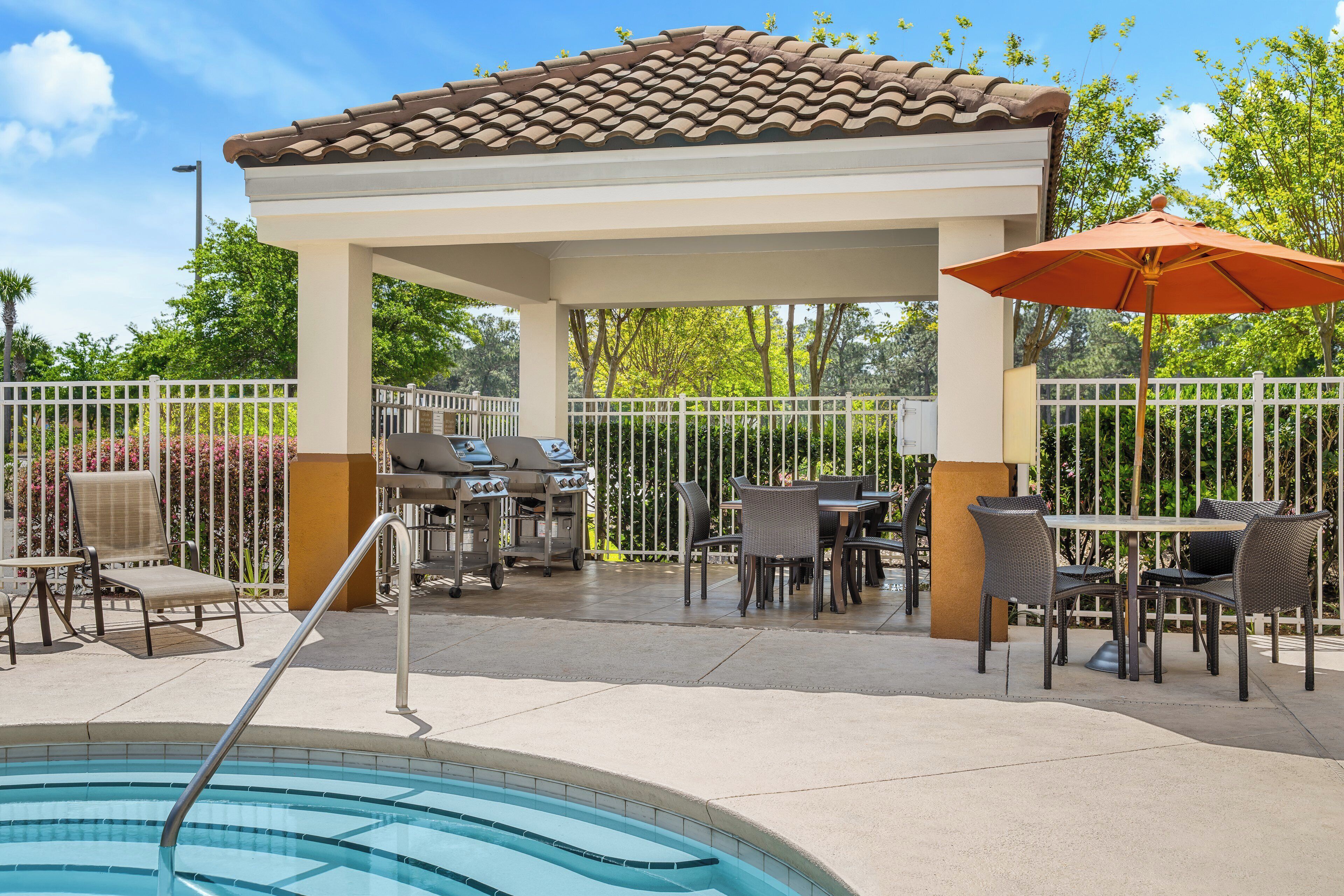 A covered outdoor area with a pool, patio furniture, and a barbecue grill.