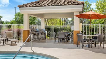 A covered outdoor area with a pool, patio furniture, and a barbecue grill.