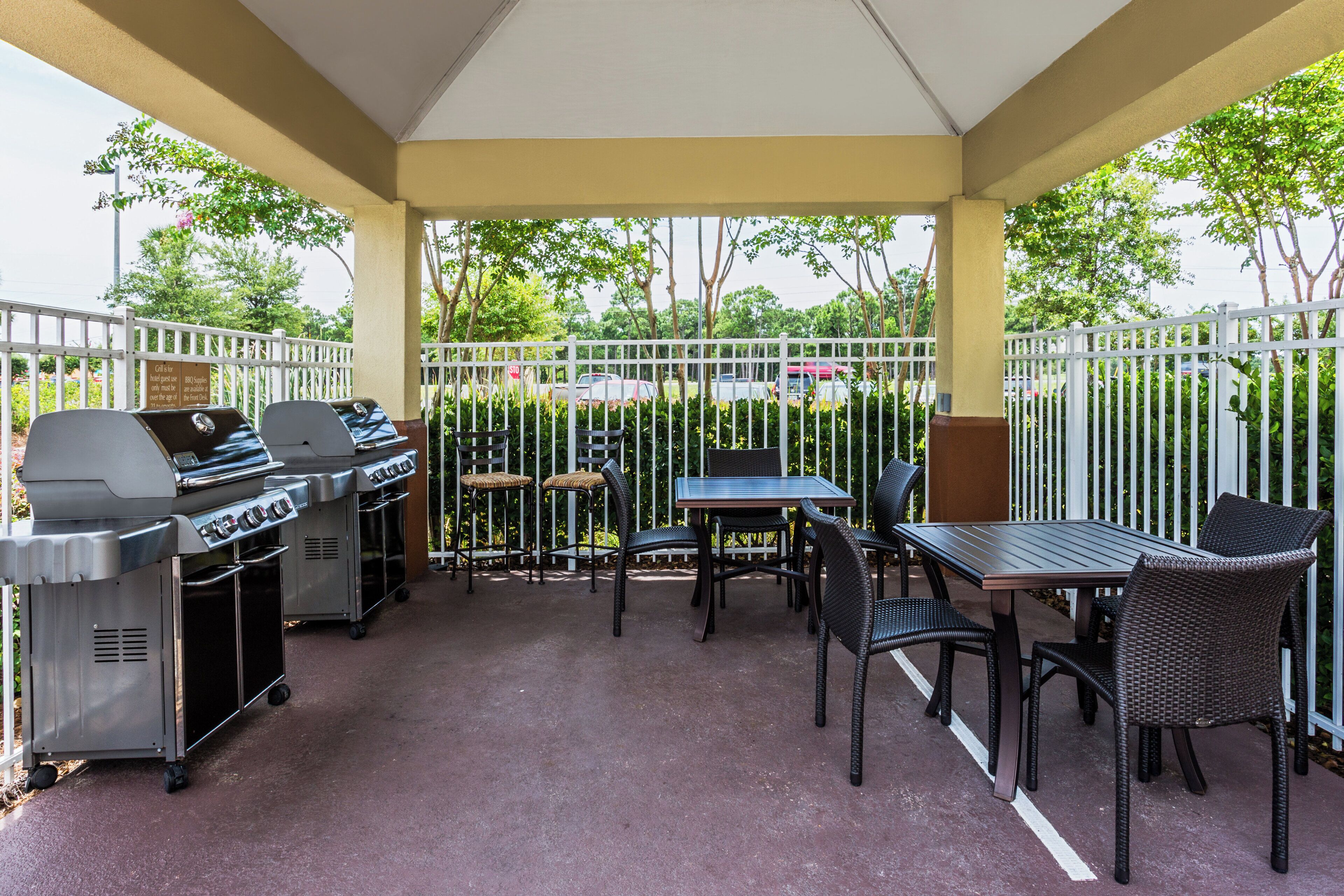 Eine Terrasse im Freien mit Grill, Sitzgelegenheiten und Blick auf die umliegende Natur.