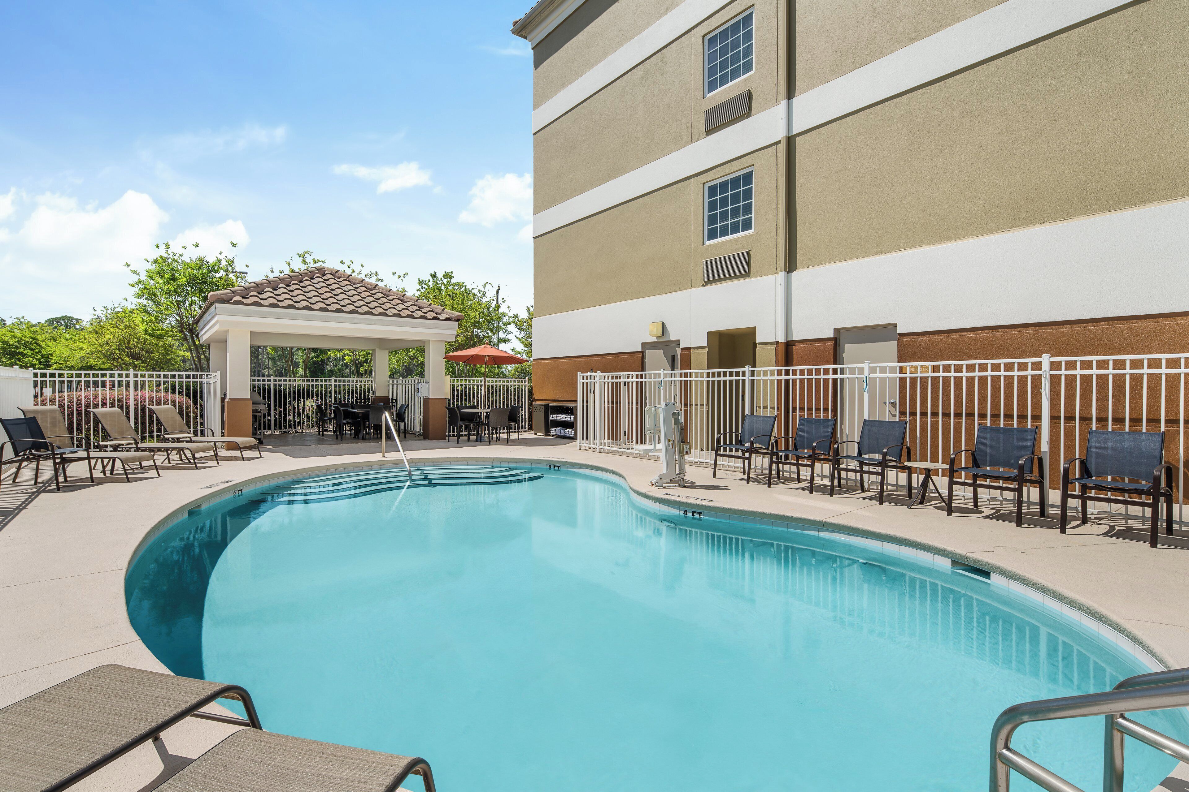 A swimming pool with lounge chairs and a covered seating area.