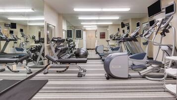 A gym with various exercise equipment, including treadmills, ellipticals, and weight machines.