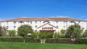 Un hotel amb un rètol que diu 'CANDLEWOOD SUITES' davant d'un edifici amb teulada de rajoles i nombroses finestres.