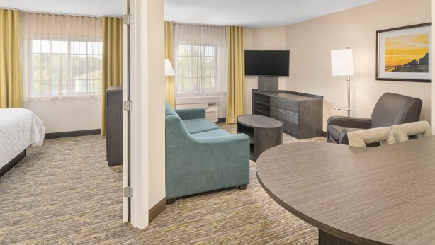 A hotel room with a bed, a sofa, a TV, a desk, and a dining table. - Candlewood Suites Destin-Sandestin by IHG (Miramar Beach)