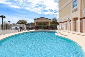 A swimming pool with a gazebo, surrounded by a white fence, and a building with a beige facade. - Candlewood Suites Destin-Sandestin by IHG (Miramar Beach)