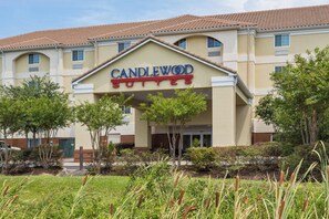 A hotel named Candlewood Suites with a beige facade and a red-tiled roof.