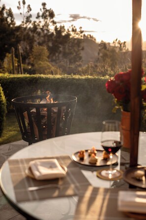 A round table with a plate of food, a glass of red wine, and a candle.