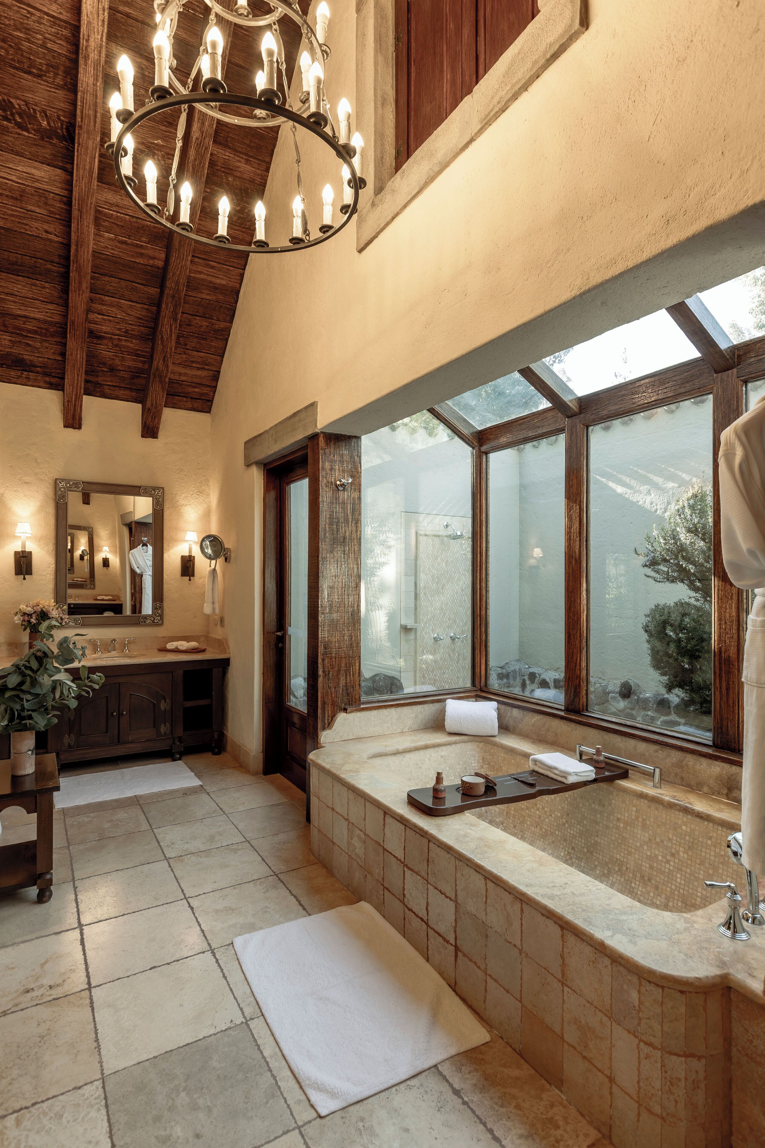 A spacious bathroom with a large bathtub, a wooden ceiling, and a large mirror above the sink.