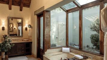 A spacious bathroom with a large bathtub, a wooden ceiling, and a large mirror above the sink.
