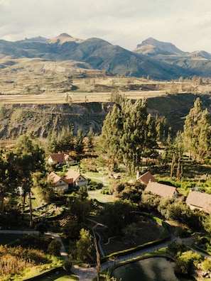 A residential area with terraced fields, houses with red-tiled roofs, and a mountainous backdrop.