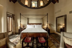 A four-poster bed with a wooden headboard, two bedside tables with lamps, a large mirror, and a patterned rug. - Las Casitas, A Belmond Hotel, Colca Canyon (Yanque)