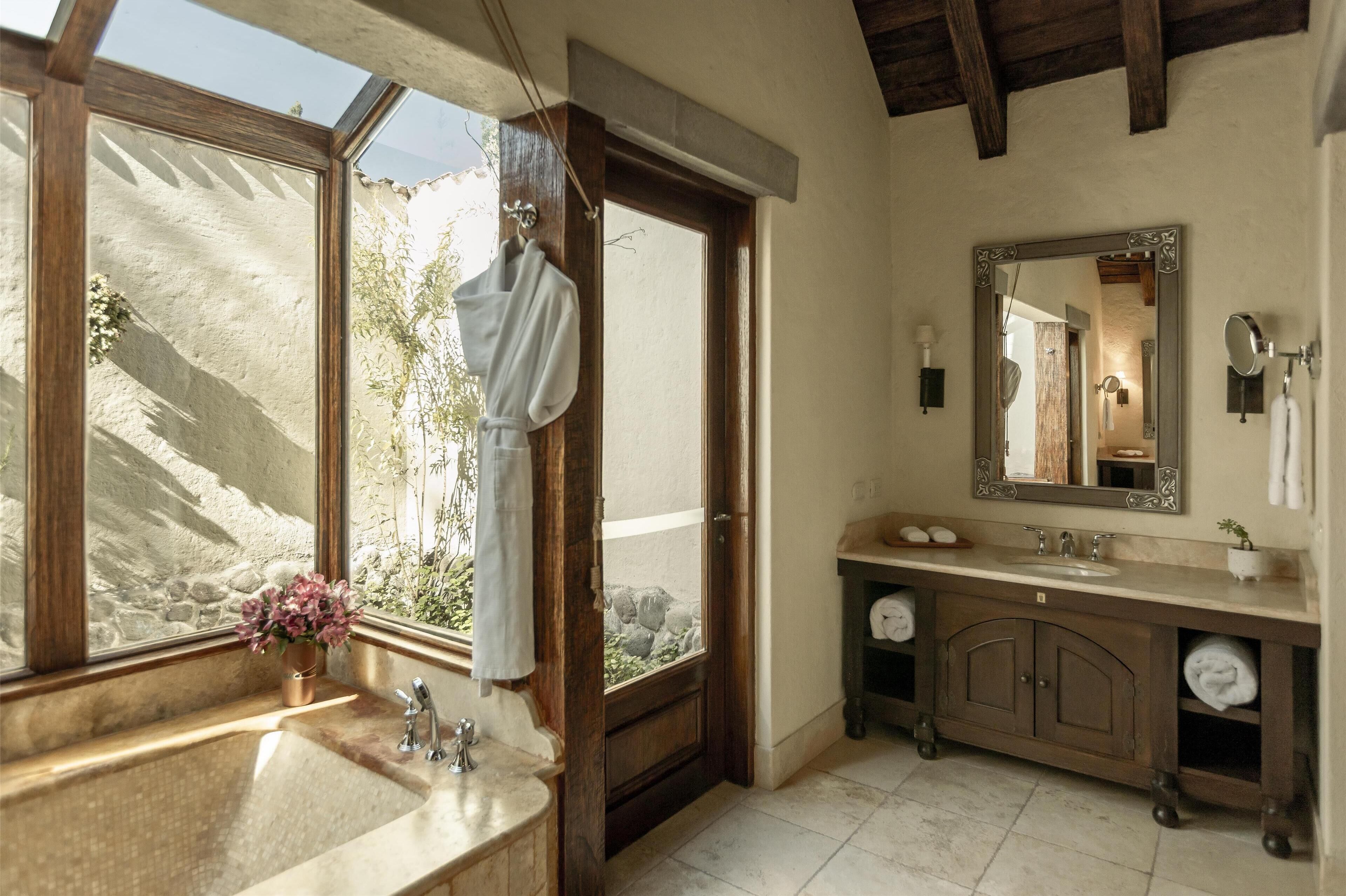 A bathroom with a large window, a sink, a mirror, and a towel rack.