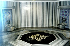 A bathroom with a marble floor, a central sink, and decorative tiles on the walls. - By Karaaslan Inn (Kusadasi)