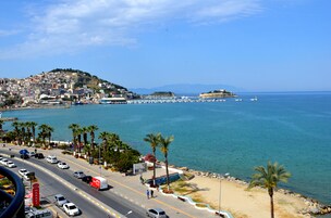 Un paisaje urbano costero con una carretera que lleva a una playa, palmeras y una isla distante.