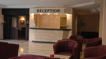 A reception area with a reception desk, leather chairs, and a potted plant.