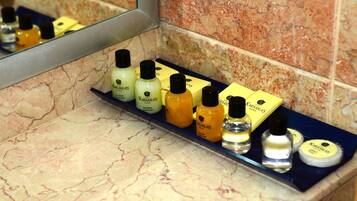 A bathroom shelf with various toiletries including a soap bar, a bottle of lotion, and a container of cream.