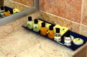 Un estante en el baño con diversos artículos de aseo, incluyendo una pastilla de jabón, una botella de loción y un envase de crema.