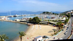 Ein Yachthafen mit Booten, einem Strand und einer Stra ße mit Autos.
