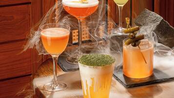 A table with four glasses of cocktails, smoke effects, and a decorative stone.