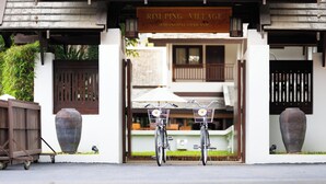 Une enseigne indiquant « RIM PING VILLAGE » est placée au-dessus d’une porte, et deux vélos sont garés devant.