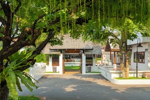 A traditional building with a covered entrance, a garden area, and a pathway leading to the entrance. - Rimping Village Hotel (Chiang Mai)