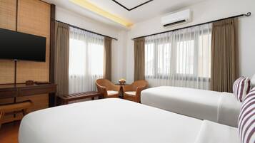 Une chambre d’hôtel avec un grand lit, deux chaises, une petite table, un téléviseur et un appareil de climatisation.