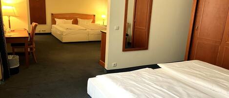 Una habitación de hotel con una cama, un escritorio con silla, un armario y un espejo.
