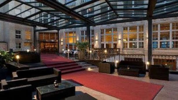 A spacious lobby with a red carpet, modern furniture, and a glass ceiling. - Wyndham Garden Berlin Mitte (Berlin)