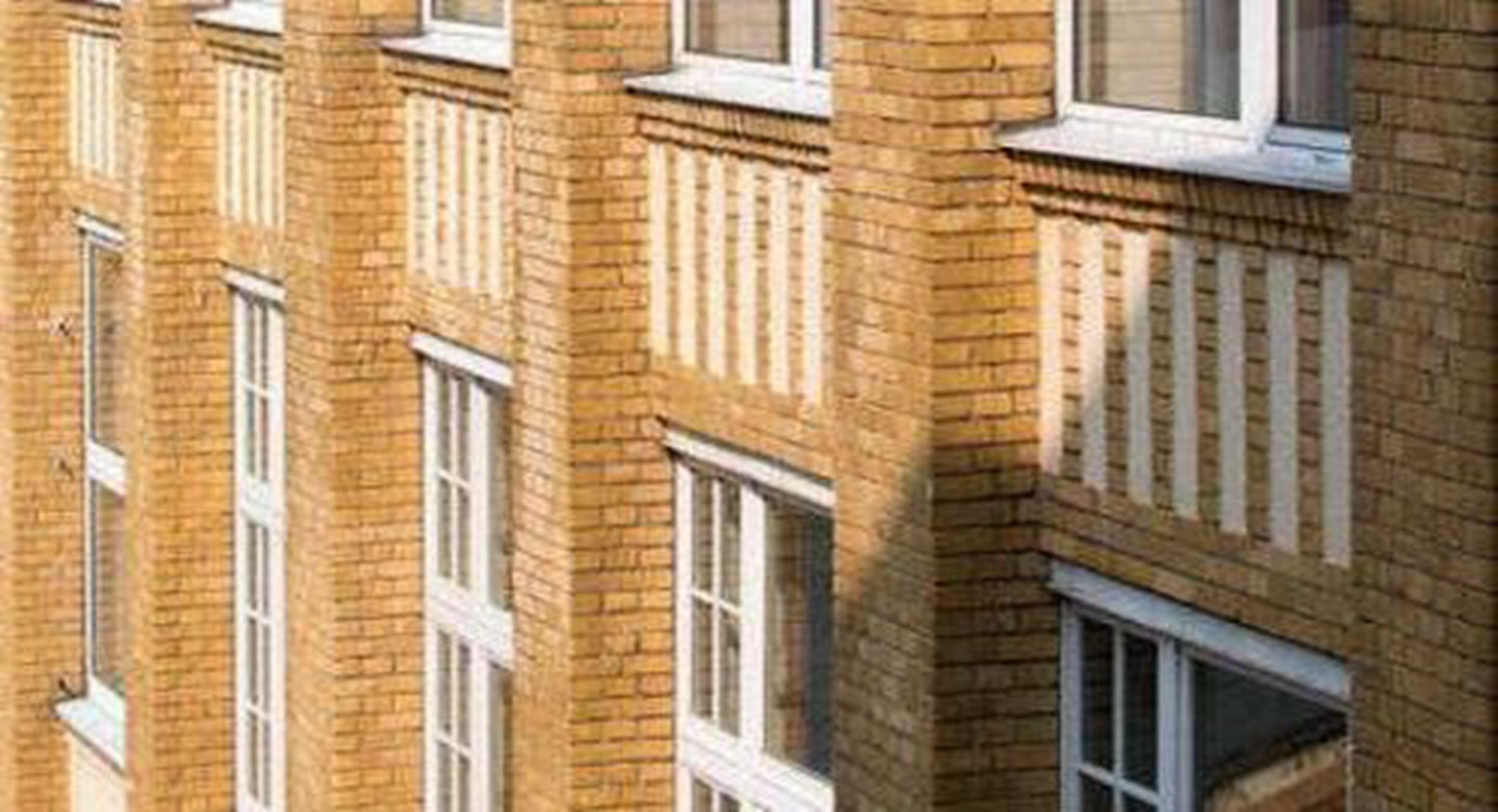 Un edifici de diversos pisos amb façana de maó i finestres d'emmarcament blanc.