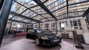 A car parked inside a building with a glass ceiling, surrounded by windows. - Wyndham Garden Berlin Mitte (Berlin)