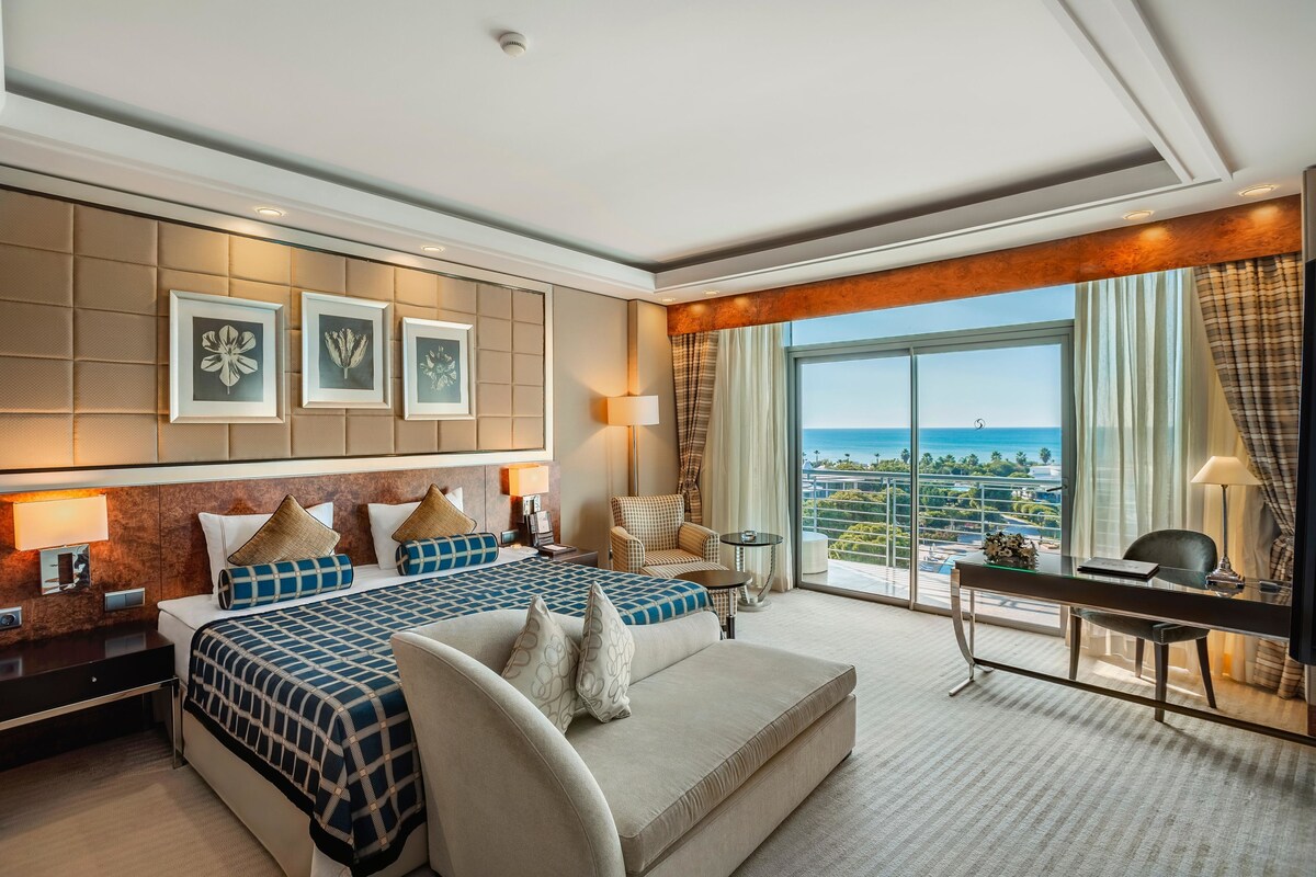 Ein geräumiges Hotelzimmer mit einem großen Bett, einem Schreibtisch und Blick auf den Ozean.