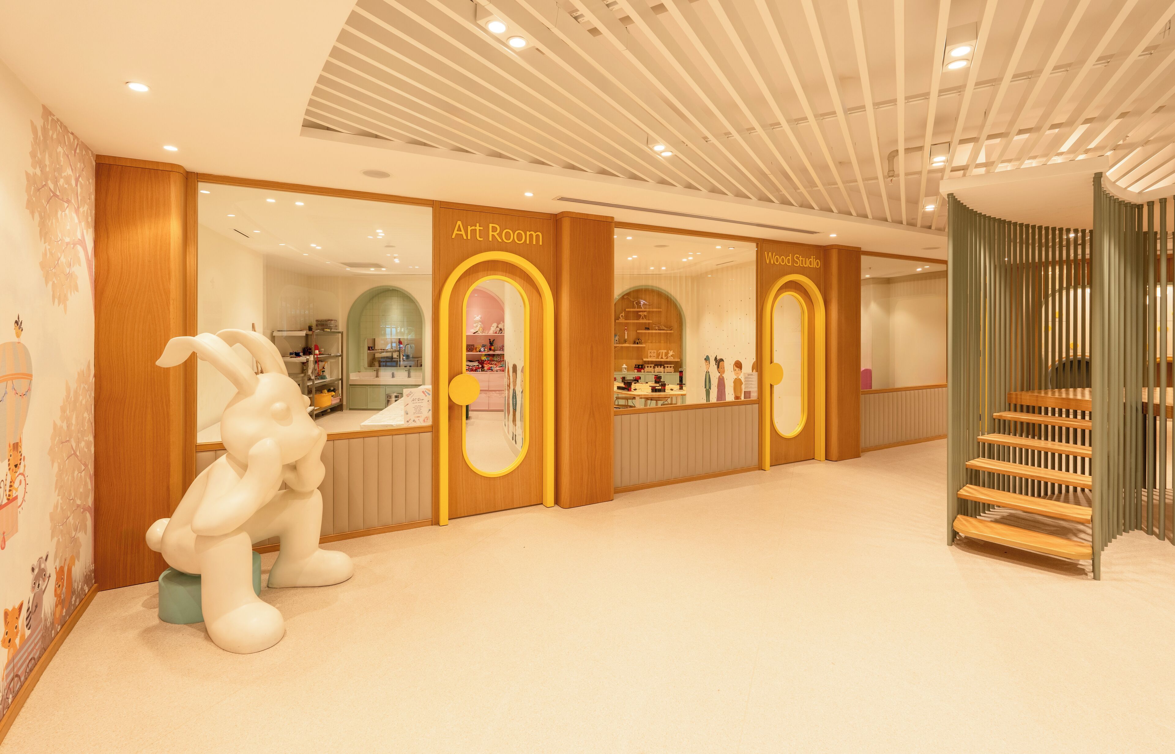 A modern interior with an Art Room and Wood Studio, featuring a central staircase and a large white sculpture.