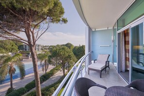 Relax on the balcony with two comfortable chairs, overlooking a serene landscape with a pool and palm trees.