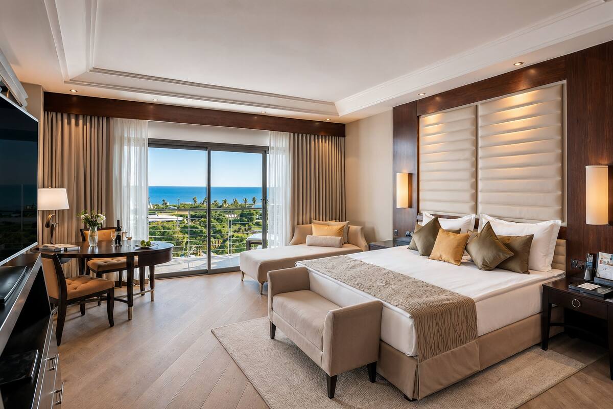 A modern hotel room with a large bed, a desk, and a view of the ocean.
