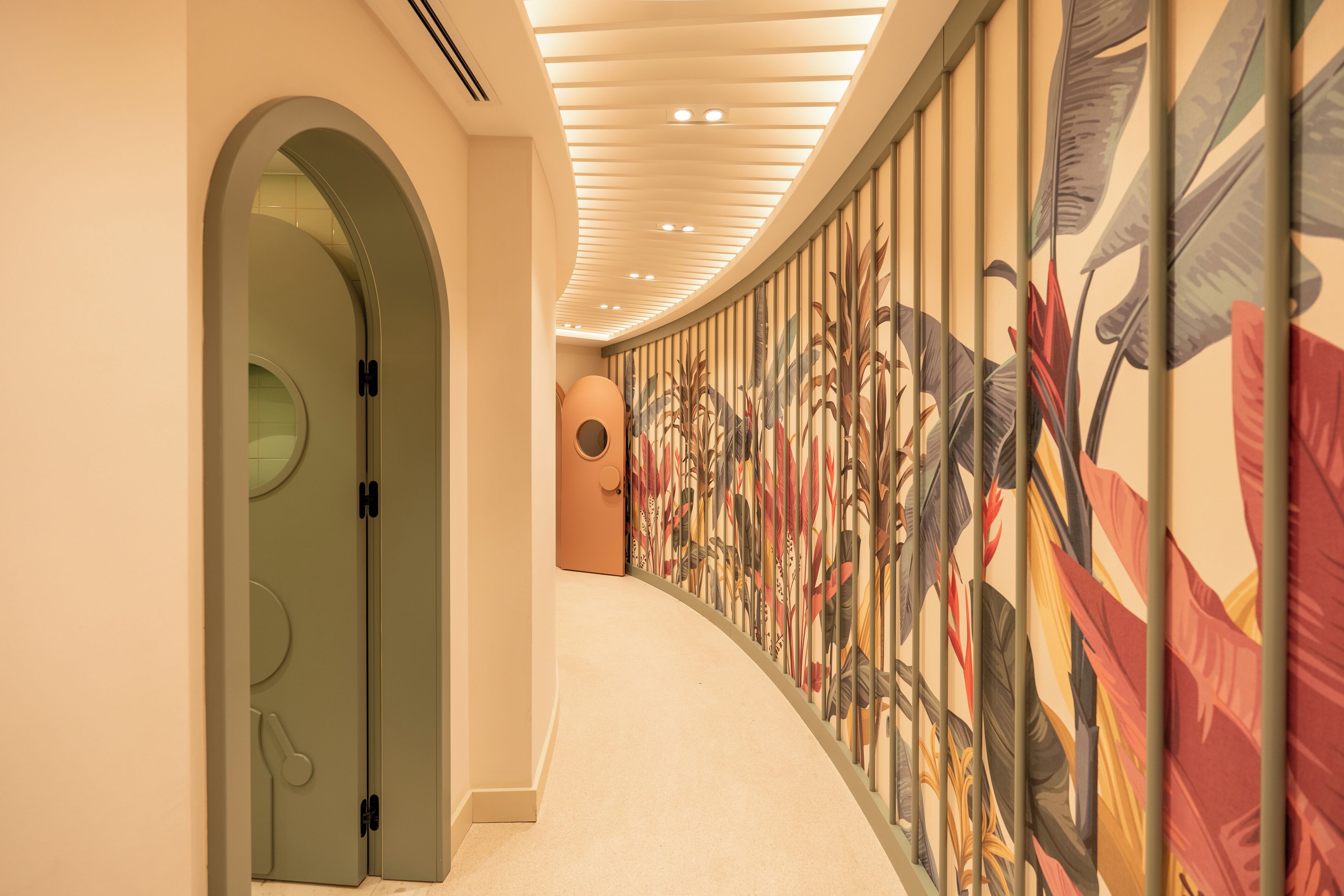 A hallway with a curved ceiling, a patterned wall, and a door with a circular design.