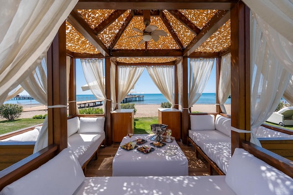 Un espacio de estar al aire libre cubierto con vistas a la playa y al muelle.