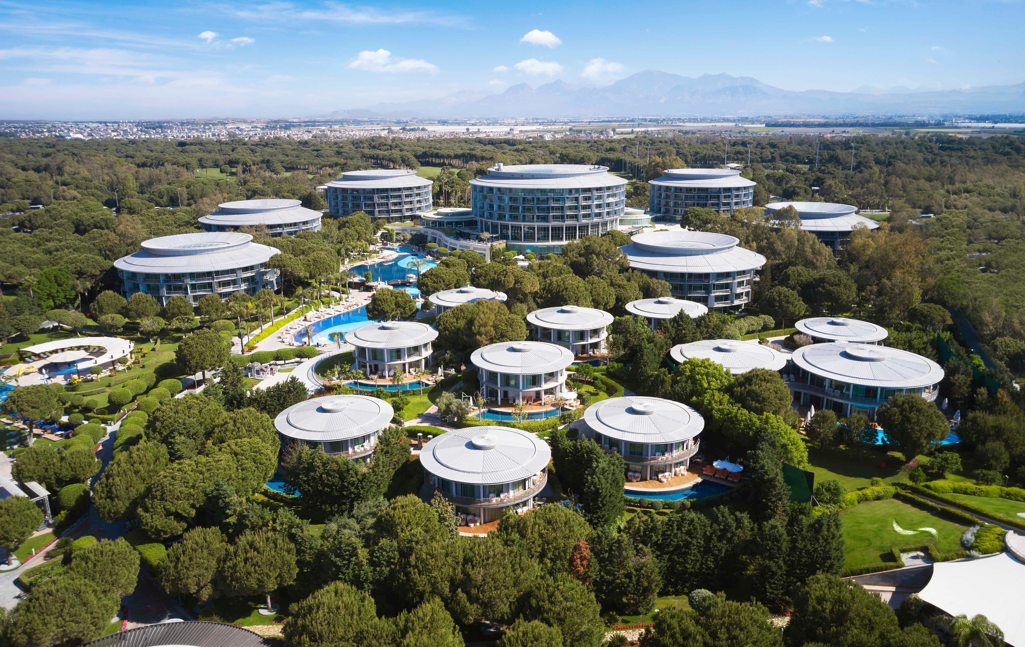 Un resort con varias edificaciones circulares, cada una con piscina y rodeada de exuberante follaje.