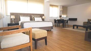 Een moderne hotelkamer met een groot bed, houten meubels, een zithoek en een televisie.