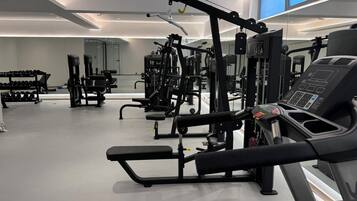 Un gimnasio moderno con diverso equipamiento de ejercicio, incluyendo una cinta de correr y máquinas de pesas.